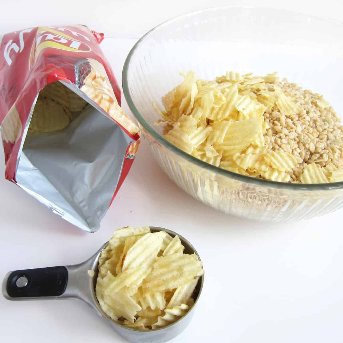 a bag of rippled potato chips set next to a large mixing bowl filled with chips and Rice Krispies cereal.